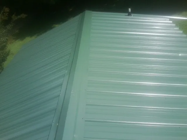 New green metal panels meeting at the ridge of a roof — Flat Roof Repair work by our crew in Malvern